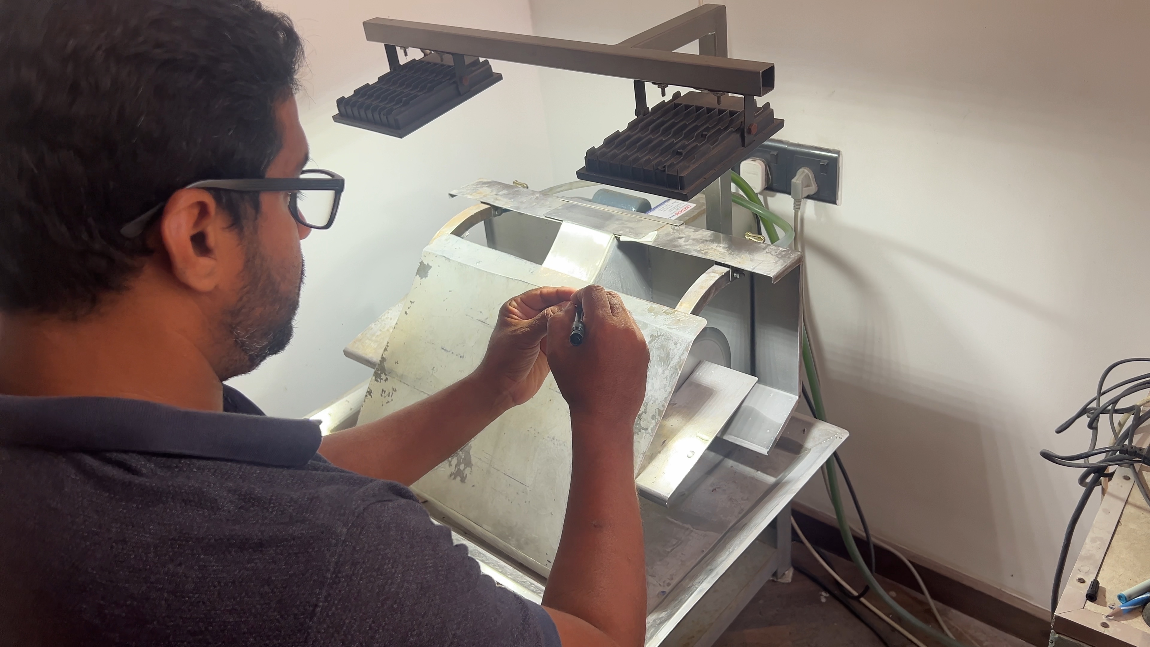 An experienced cutter holds a small stone beside lapidary equipment.