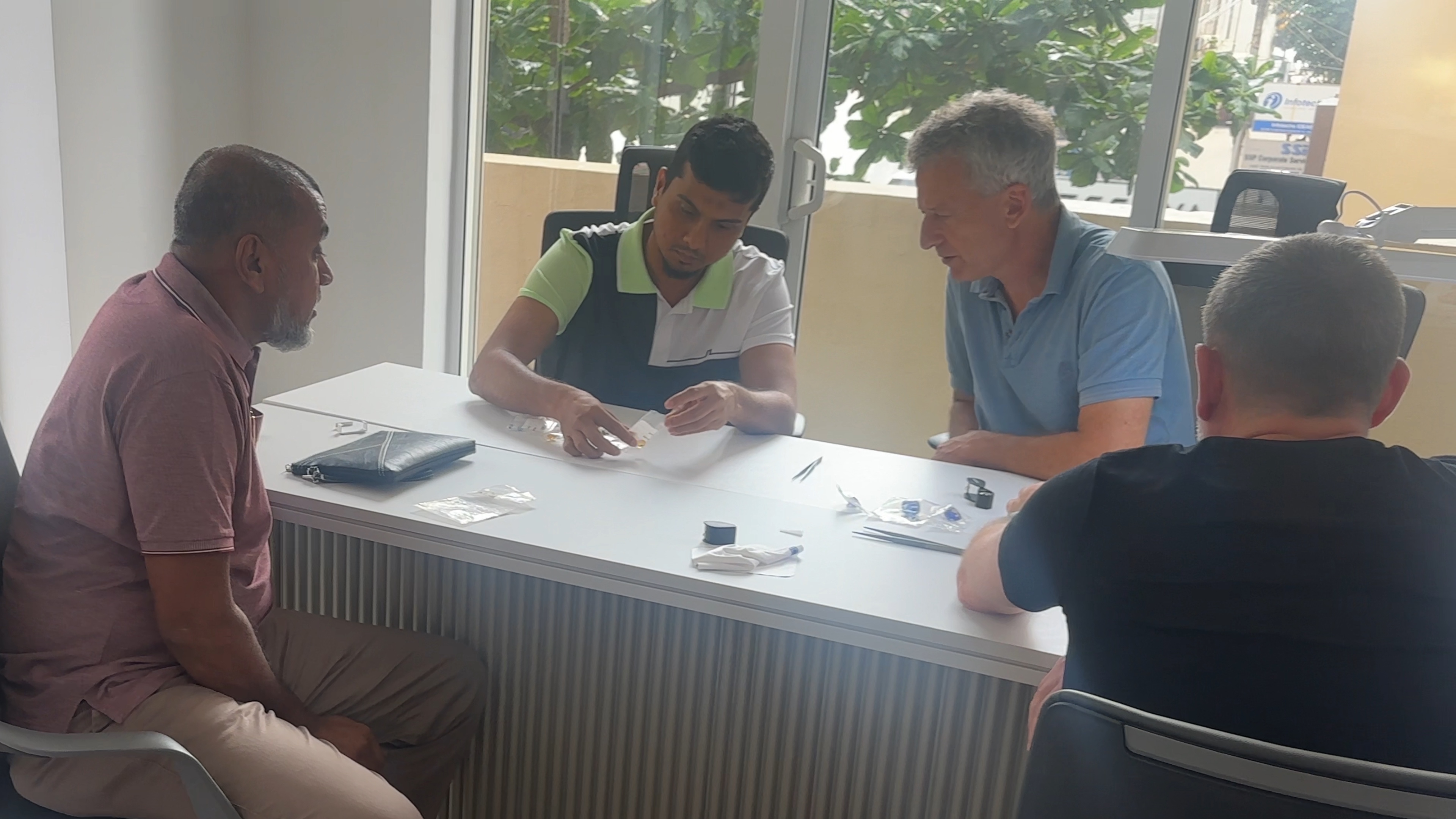 Four people gathered around a table during a working session, examining material together.